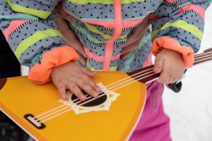A young child playing a toy balalaika