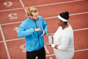Young professional sports trainer consulting woman before preparing for competition