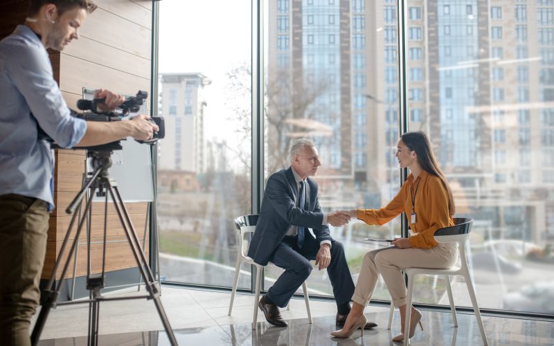 Team of reporters working on a interview with a grey-haired man